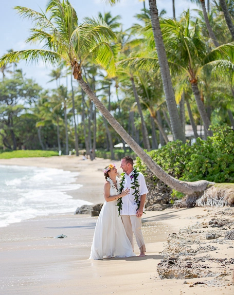 Beach wedding couple walking by the shore