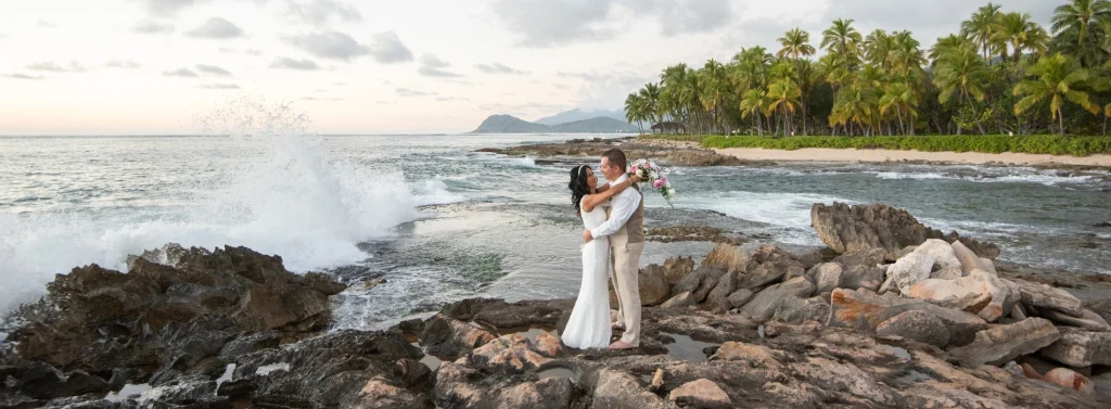 Beach wedding couple embracing on rocky shore